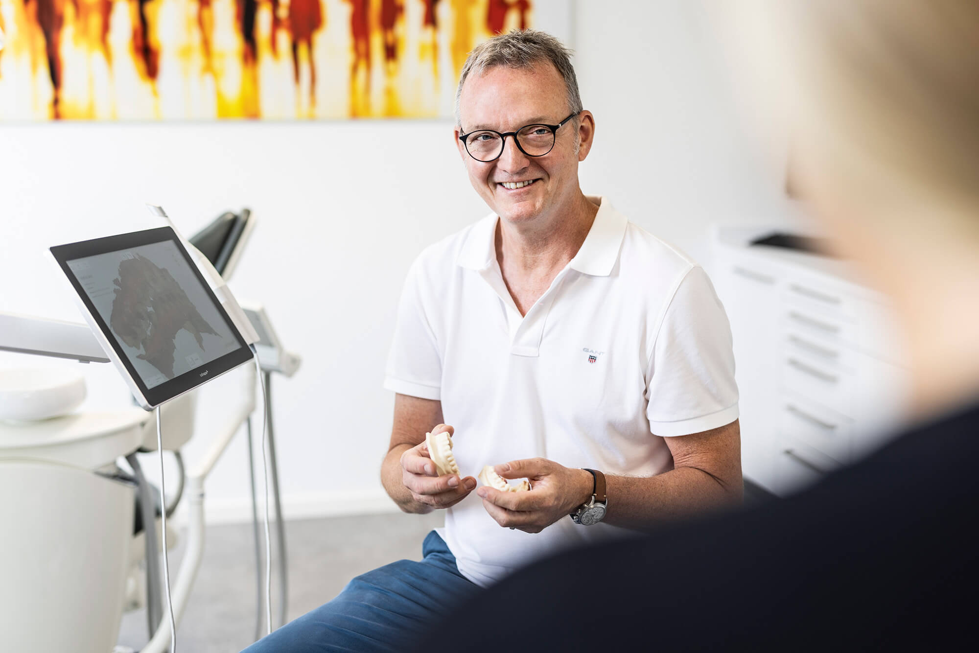 Dr. Steffen Lenz erklärt einer Patientin die Schienentherapie