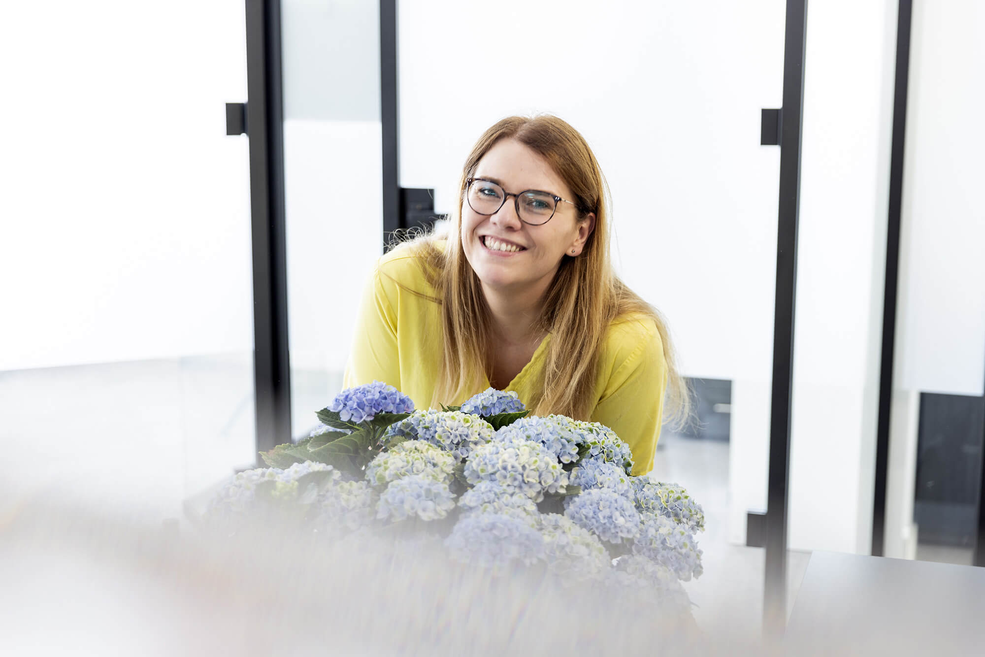 Lächelnde Mitarbeiterin vor einem Blumenstrauß